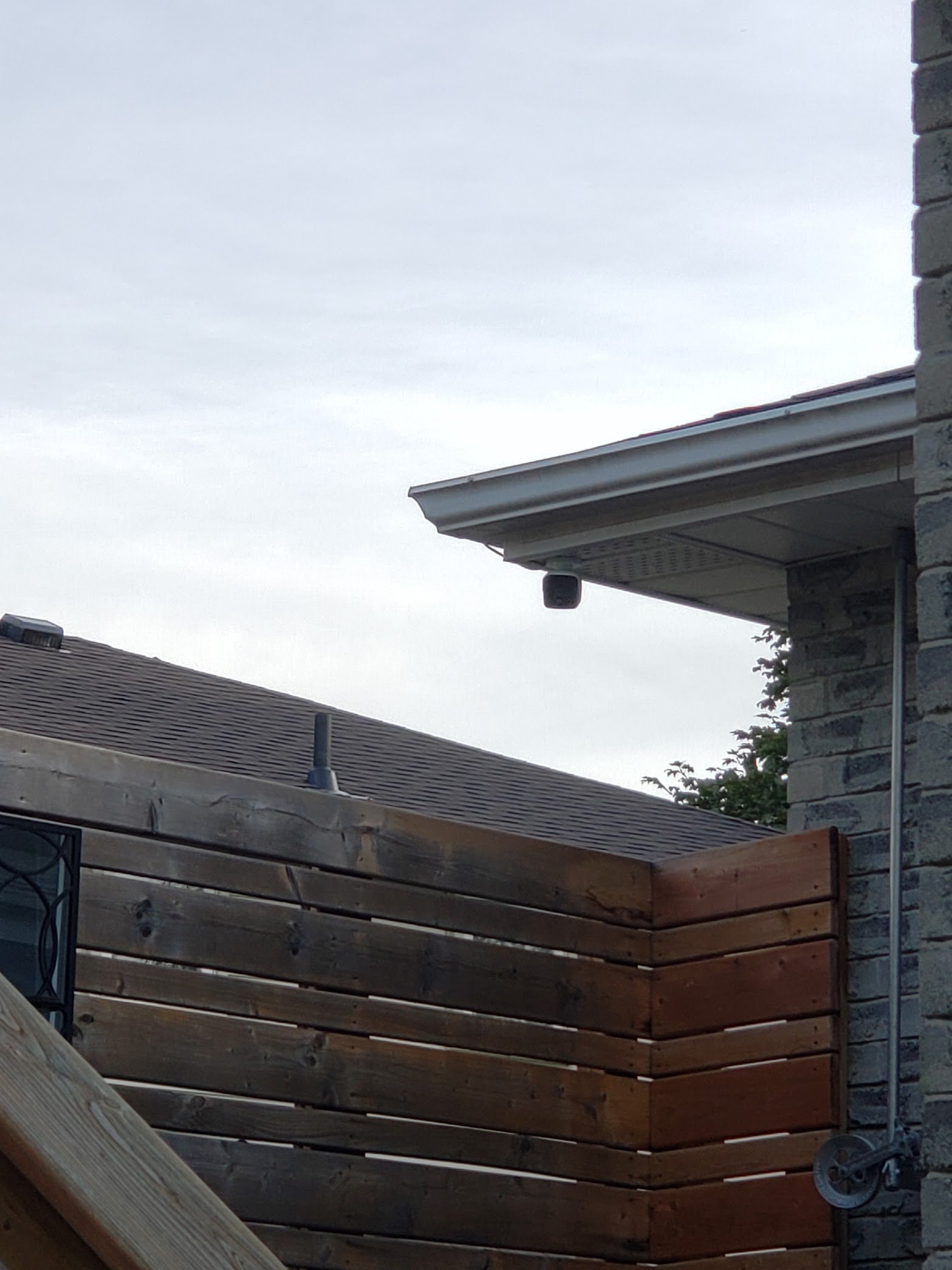 Outdoor security camera installed beneath a residential eave